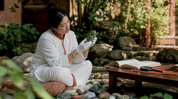 Woman examining jade sculpture at gallery table