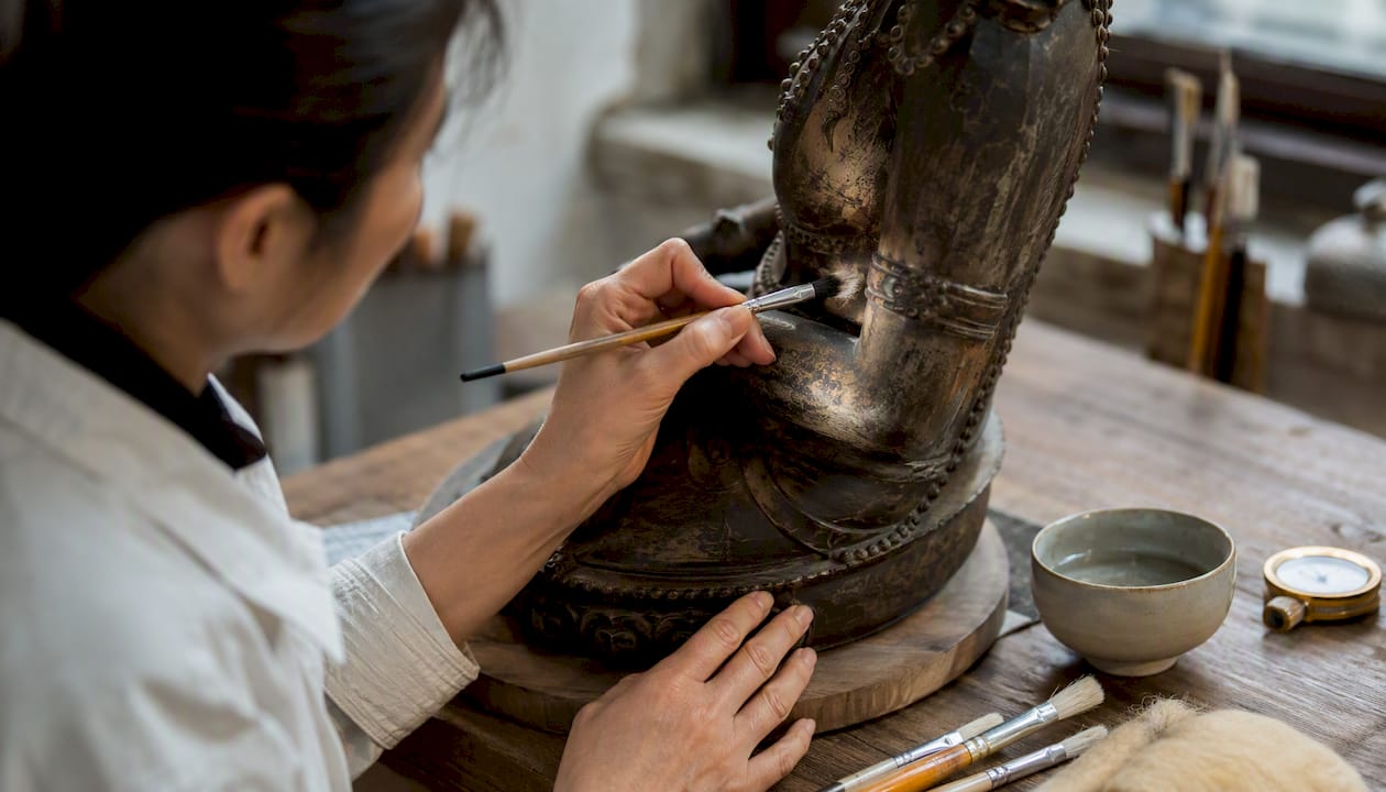 Conservator applying wax to bronze statue restoration spot