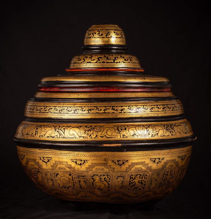 Intricate, layered Burmese black and gold bowl with ornate designs against a dark background.